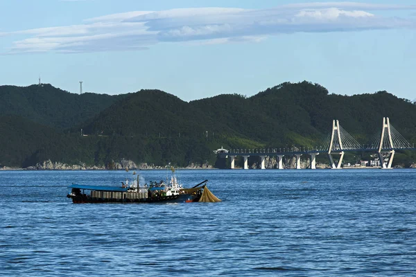 fishing boat pulls a net on the background of the bridge