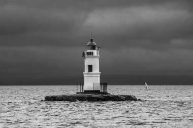 Deniz feneri Tokarevskaya Burnu kedisi Vladivostok 'ta bulutlu bir havada denizin arka planında