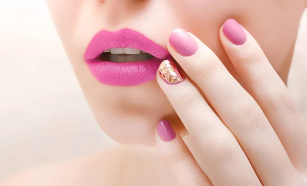 Pink lips and pink nail art. Female face closeup