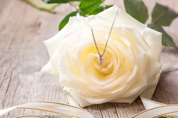 Silberne Halskette Auf Einer Weißen Rose lizenzfreie Stockfotos