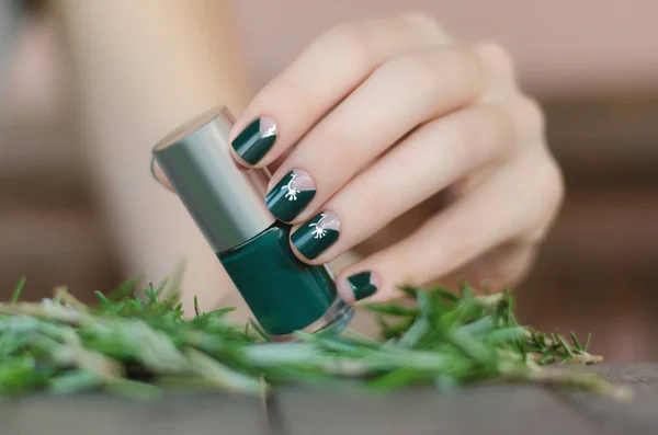 Женская рука с зеленым дизайном ногтей держа бутылку лака для ногтей — стоковое фото