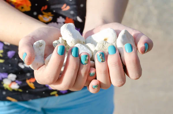 Kobieta ręka z niebieskim paznokci projekt gospodarstwa kamienie morskie — Zdjęcie stockowe