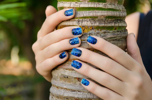 Female hand with blue nail art stickers