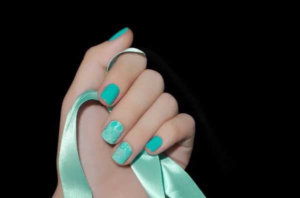 Mão feminina com design de unhas verde segurando fita verde — Fotografia de Stock