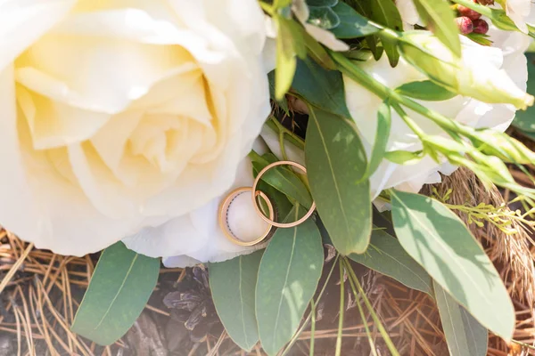 Anillos de boda en una rama de abeto verde y ramo de flores —  Fotos de Stock