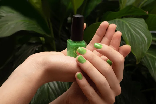 女性手与绿色指甲设计举行指甲油瓶. — 图库照片