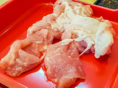 Kırmızı tabakta çiğ domuz göbeği