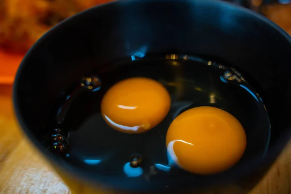 Clara de huevo amarillo e ingrediente para hornear yema en un tazón negro —  Fotos de Stock