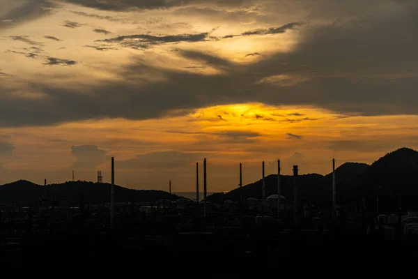 Refinería de petróleo o gas al atardecer. Una silueta de una refinería industrial de petróleo o gas al atardecer con un cielo colorido detrás —  Fotos de Stock