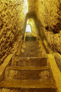 Bir mağaraya merdiven boşluğu. Kayanın içine el oyması bir tünelde merdivenler. Stone, Endonezya 'nın Bali adasında yer altına iniyor. Goa Giri Campuhan Şelalesi, Bali, Endonezya 'daki yeraltı geçidi tüneli..