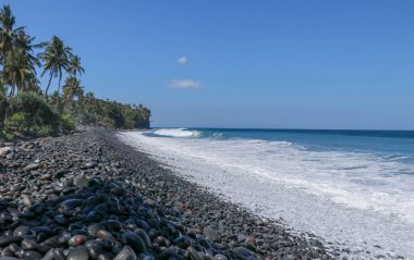Siyah çakıl taşlı tropik plaj. Kayalık bir sahili olan Bali adası. siyah kumsal Endonezya