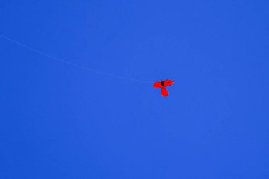 Koyu mavi gökyüzünün arka planında uçurtma. Koyu mavi gökyüzünde kırmızı uçurtma. Metnin için boşluk.