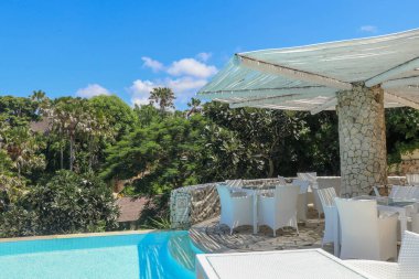 Endonezya, Bali 'deki ultra modern otelin havuz alanında. Oturacak ve şemsiyenin altında dinlenecek bir yer..