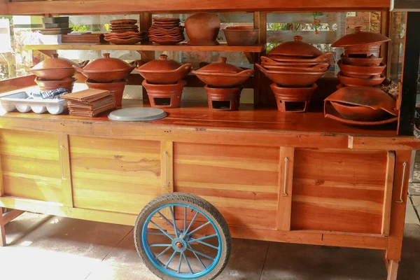 Tontopf mit Gewürzen und Zutaten auf dunklem Hintergrund. asiatisches Essen, gesundes oder Kochkonzept. Holzwagen mit großen Tontöpfen darin — Stockfoto