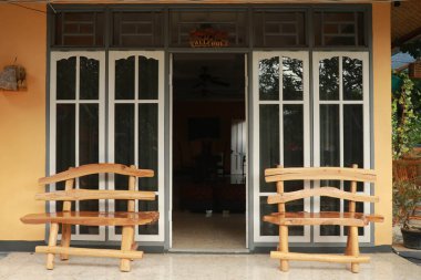 Bir evin ahşap ön kapısı. Penceresinde yansımalar olan sarı bir evin ahşap ön kapısının ön manzarası ve veranda ve ön geçit geniş bir görüş açısı. Yatay çekim.