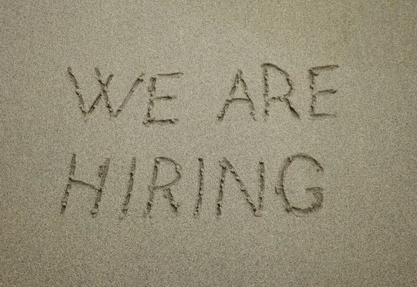 we are hiring, concept on the beach. concept text written on sand.