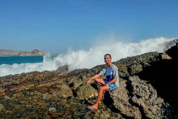 티셔츠와 파란색 반바지를 젊은이가 바위가 해변에 있습니다 이것은 사람의 모습입니다 — 스톡 사진