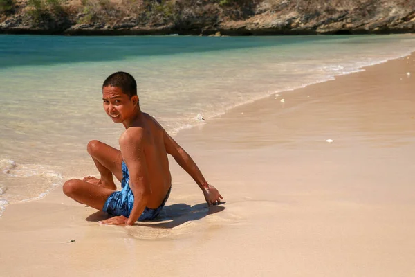 Portrait d'un jeune homme attrayant sur une plage tropicale. Concentration sélective jeune homme assis sur la plage, copier l'espace. Asiatique adolescent assis sur une plage de sable et regardant dans l objectif — Photo