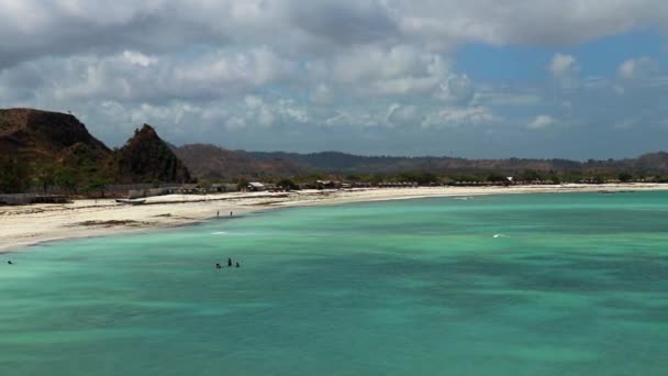 Μια περιοχή, drone shot του ειδυλλιακού headland στην παραλία Tanjung Aan στο Lombok, Ινδονησία. Ο κόλπος του νερού περιβάλλεται από βράχια. Το νερό έχει πολλές αποχρώσεις του μπλε. Ιδανική μέρα για χαλάρωση στην παραλία — Αρχείο Βίντεο