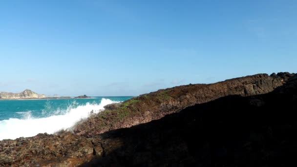 Kék Csendes-óceáni hullámok csapódnak vulkanikus sziklák partján Tanjung Aan, Lombok, Indonézia
