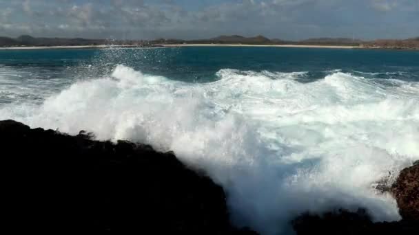Las olas del mar se rompen en rocas peligrosas en la orilla del mar. Limpien el agua espumosa sobre las piedras, la tormenta oceánica — Vídeo de stock