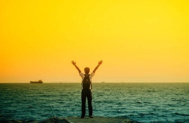 Asyalı adam denizin kenarında duruyor. 