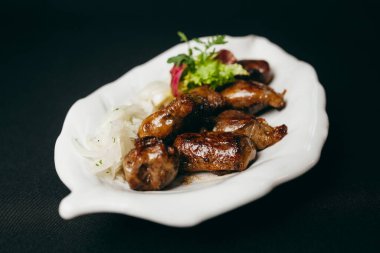 Tabağında yeşil yapraklar olan lezzetli kızarmış domuz eti.