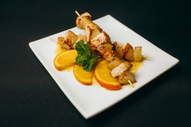 Tavuklu şiş ve tabağında portakal dilimleri olan patates.