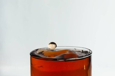 Bardağa biraz içki dökerek. 