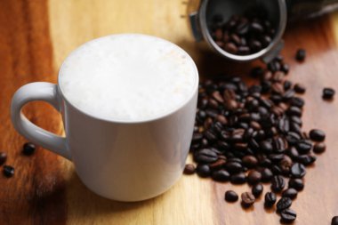 Sıcak latte, sıcak kahve ve ahşap zeminde süt köpüğü