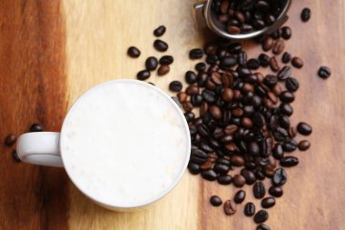 Sıcak latte, sıcak kahve ve ahşap zeminde süt köpüğü