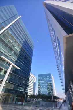 Modern bir bölge olan yüksek katlı iş ile metropol merkezi binalar büyük cam pencereli, aralarında mavi gökyüzünde uçan uçak. 10mm (balık gözü)