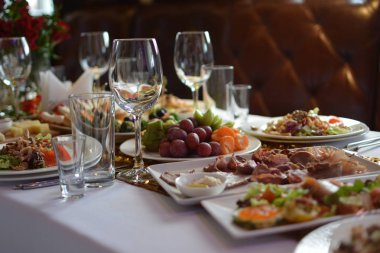 Küme beyaz bez gıda, kırmızı lüks buketleri, ferahlık, tabak ve gözlük dolu bir festival düğün tabloyla yakın çekim tarafından mor deri Koç
