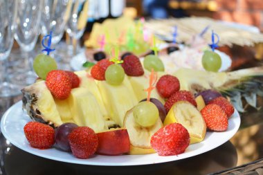 Festival meyve tabağı çilek, üzüm, ananas ve muz kanepe kanepe-yatak ile dekore edilmiş dekoratif swords ve kılıç