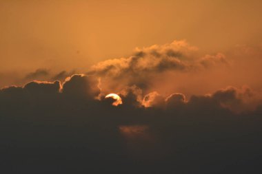 Bulut kenarları satırı tersine sıcak turuncu kırmızı renk tonlarını güzel günbatımı güneşli ray ışıklı