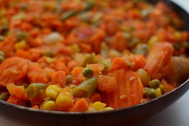 Pişmiş sebze karışımı kesilmiş ve dilimlenmiş mısır, havuç, bezelye, yeşil fasulye, sıcak bir tavada tatlı biber üst görünümü makro yakın malzemeler içeriyordu