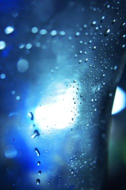 koyu mavi renklerde arka ışıkta şişenin cam yüzeyinde düşer