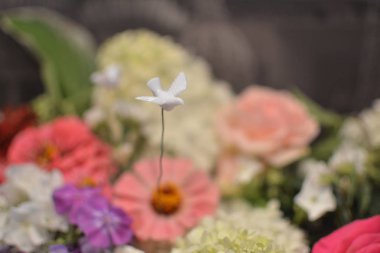 Renkli çiçekler bir buket üzerinde bir tel üzerinde yükselen beyaz güvercin küçük bir yapay rakam kadar yakın