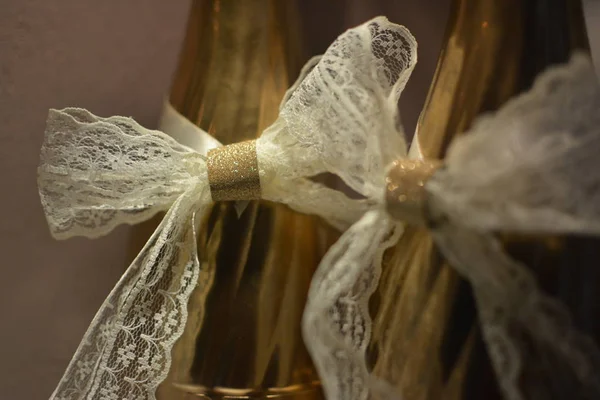 白いレースの弓で飾られた2つの金色の結婚式のシャンペーンボトルクローズアップ — ストック写真