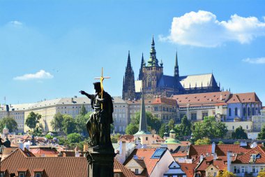 Prag, Çek Cumhuriyeti - 24 Temmuz 2018: Charles köprüsünden Vaftizci Yahya heykeline, St. Vitus Katedrali'ne ve renkli antik evlere güneşli manzara 
