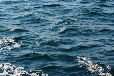 Düşük dalgalar vurgular ve deniz köpüğü arka plan zengin su renkleri ile yakın dalgalanan berrak mavi okyanus su yüzeyinin soyut doku