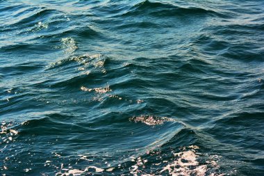 Düşük dalgalar vurgular ve deniz köpüğü arka plan zengin su renkleri ile yakın dalgalanan berrak mavi okyanus su yüzeyinin soyut doku