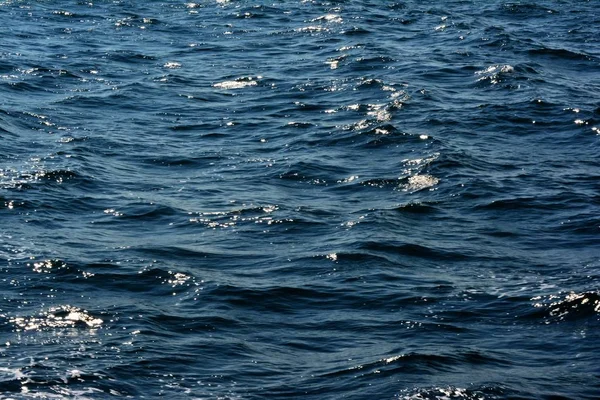 Abstract texture of sparkling rippling clear blue ocean water surface with low waves highlights background close up with rich aqua colors