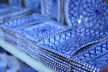 Geleneksel mavi süsboyalı ve bir pazar raf Üzerinde sırlı doğal kilden yapılmış alışılmadık formu ile benzersiz el yapımı tracery oryantal çanak çömlek plakaları yakın bir satır diyagonal görünümünde ayarlanmış