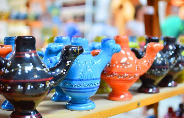 Unique handmade tracery oriental traditional pottery souvenirs made of natural clay painted to red, blue and black colors and glazed on a market shelf set in a row close up