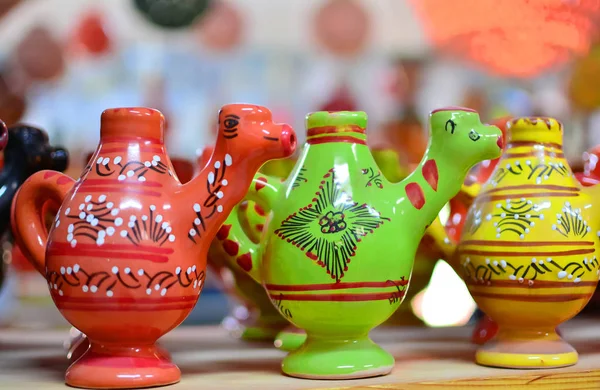 Unique handmade tracery oriental traditional pottery souvenirs made of natural clay painted to red, green and yellow colors and glazed on a market shelf set in a row close up