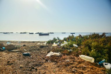 Kirli peyzaj çöp çok, çöp, güneşli bir parlak günde birçok tekne ile deniz plajında boş plactic şişeler. İnsanların dikkatsizliğini ve doğa kirliliğini ihmallerini gösteriyor.
