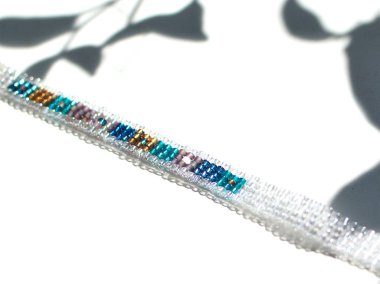 Yaprakları gölgeler ile beyaz arka plan üzerinde Köpüklü boncuklu el yapımı takı bilezik. Çok renkli cam boncuklar ile yapılan çok parlak ve güzel dekorasyon