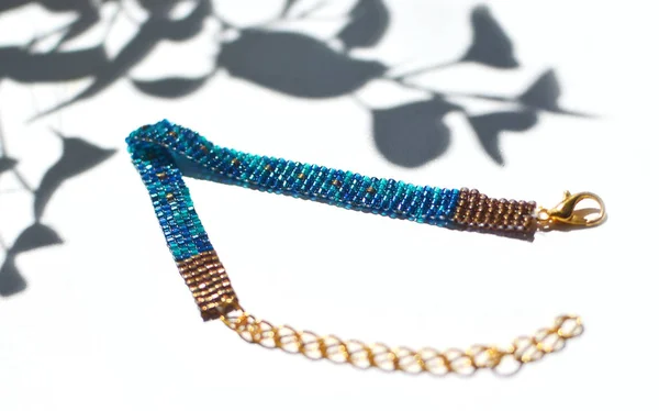 闪闪发光的珠子手工珠宝手镯在白色背景与叶子阴影 非常闪亮和可爱的蓝色装饰与可调的长度与龙虾扣和金链轻松固定 — 图库照片