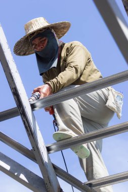 Chiang Rai, Tayland - 20 Ağustos: şapka ve elektrikli matkap çatıda 20 Ağustos 2018 üzerinde Chiang rai, Tayland kullanarak maskesi ile yakın çekim tanımlanamayan karides erkek çatı tamircisi.